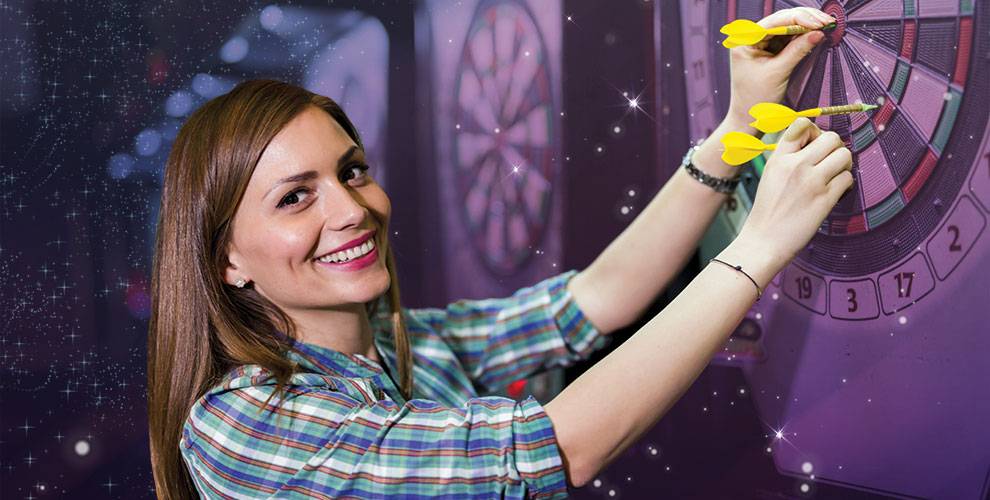 Woman smiling while removing darts from a dart board